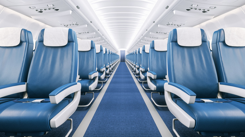 The bright interior of an unidentified commercial airplane, featuring clean, blue leather seats