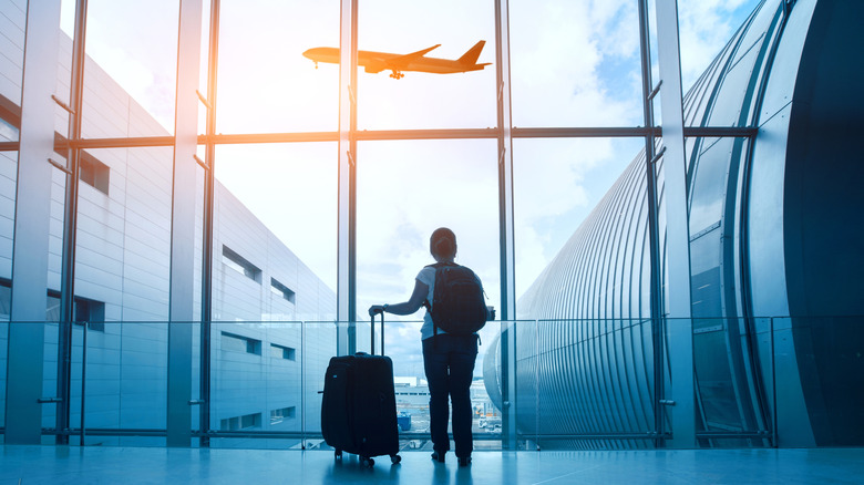 Woman at the airport watching a plane fly