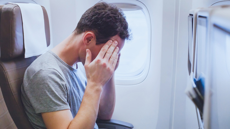 passenger hands on face flight