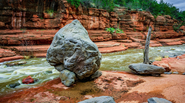 A giant gray boulder sits at the edge of Oak Creek at Slide Rock State Park near Sedona Arizona