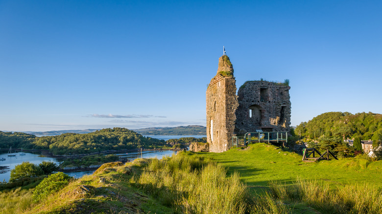 Tarbert Castle ruins with green hills, loch views, and blue sky.