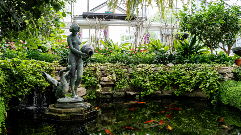 Vibrant greenhouse with copper statue and koi pond
