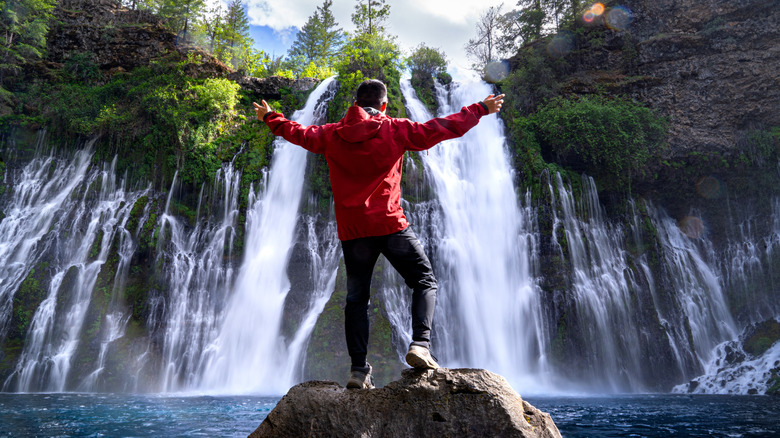 Man standing in front of waterfalls as McArthur-Burney Falls Memorial State Park