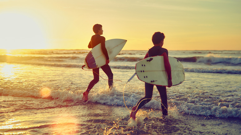 Two kids going to surf at sunset