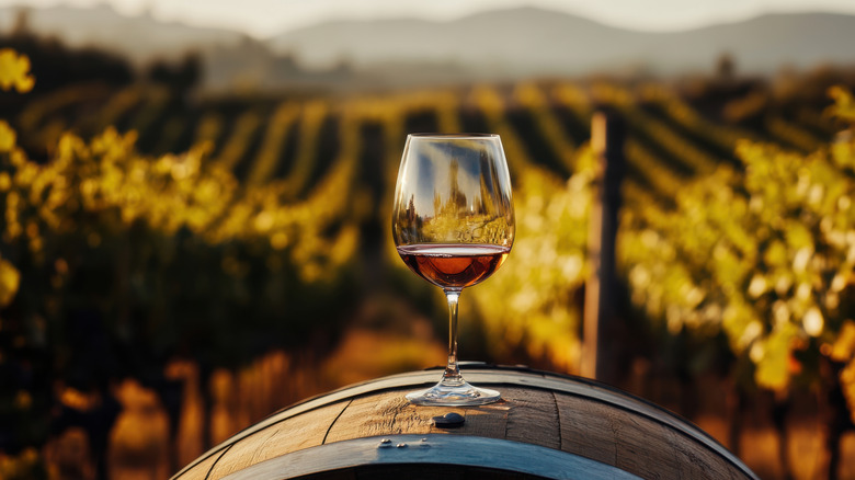 Glass of wine sitting on a wine barrel
