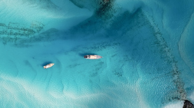Aerial view of two yachts in clear water, anchored between sandbars in the Bahamas