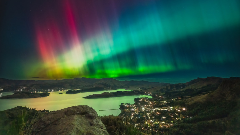 Colorful ribbons of the aurora australis over a coastal town of New Zealand at night