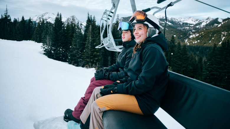 Two people on a ski lift in the mountains