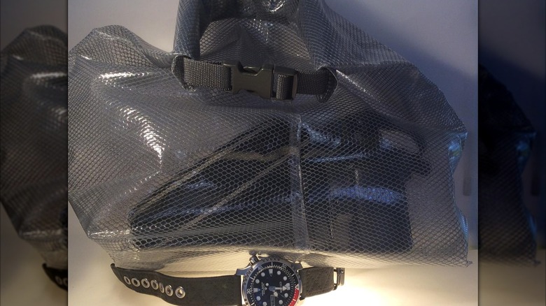 A camera in the Ikea Rensare Waterproof Bag next to a watch.