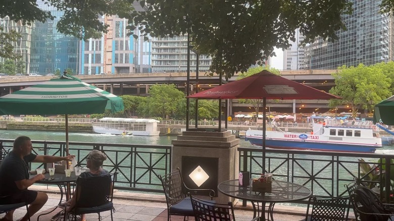 People sitting and boats going by on the Chicago Riverwalk