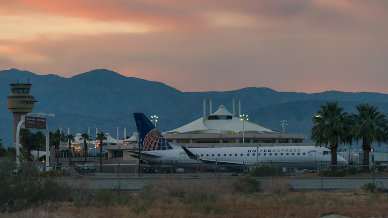 Sunset over the mountains behind Palm Springs International Airport with a United Express plane in front.