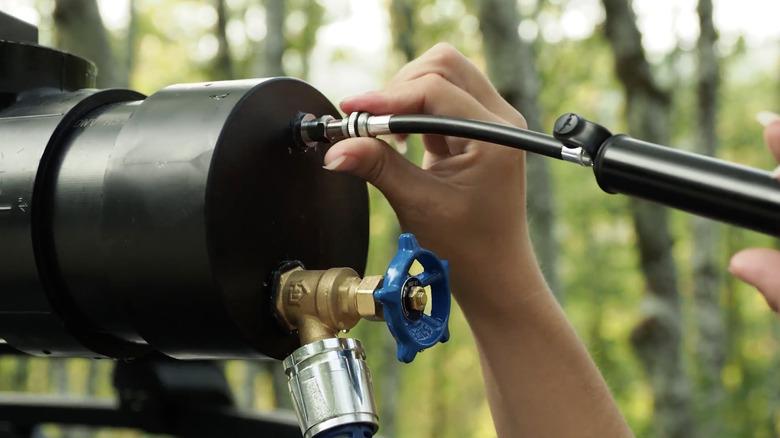 A person's hands pressurizing a DIY shower with a bike pump