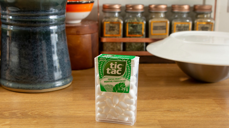 A Tic Tac container in front of a spice rack