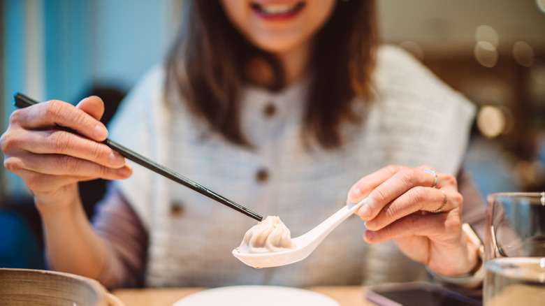 A woman enjoying xiao long bao (Chinese soup dumpling)