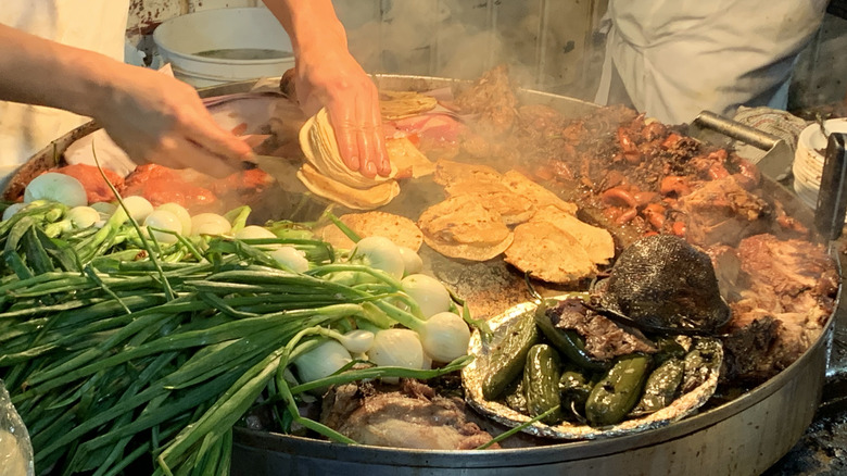 Someone preparing street food on a large grill in Mexico City