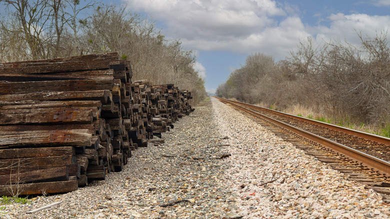 Empty railroad tracks with old wood stacked along one side