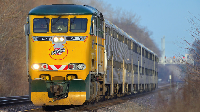 A yellow commuter train passes through Glen Ellyn en route to Chicago
