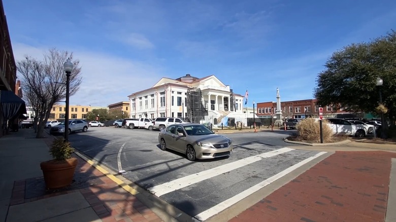 A blue-sky day in Laurens with the public square, cars, and a historic white building in the center.