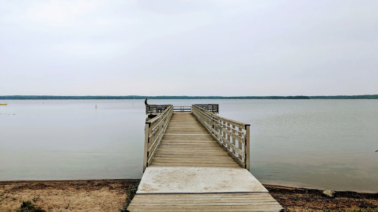 A dock extending over glassy water from a beach at Shell Lake, Wisconsin.
