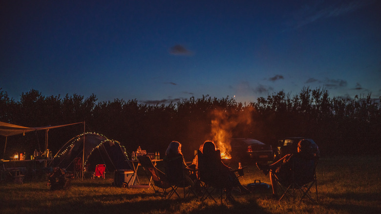 Friends outside sitting around campfire