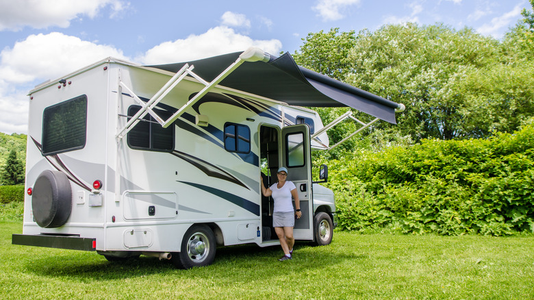 A woman standing under the awning of an RV