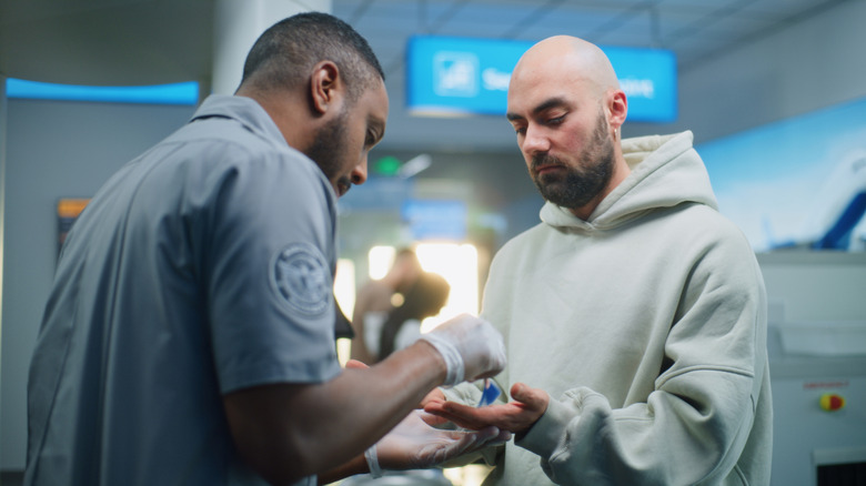 Man in a hoodie getting checked at TSA