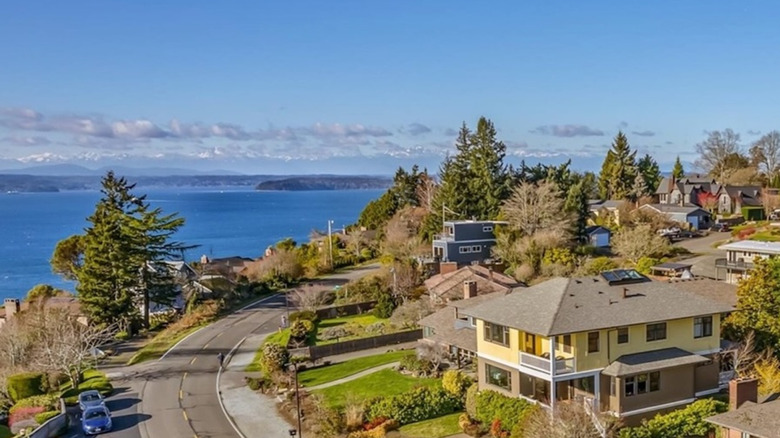 Large yellow house on windy road in sunny, coastal neighborhood