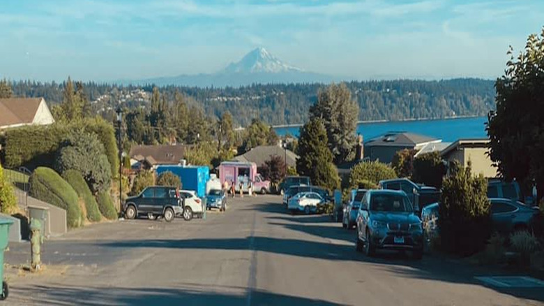 Downhill slope of neighborhood street with cars and view of Mount Olympus