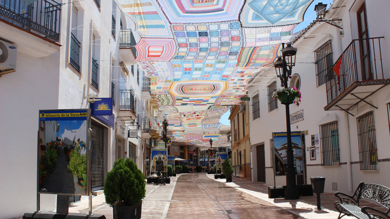 Pedestrian shopping street shaded by a mutli-color crocheted awning