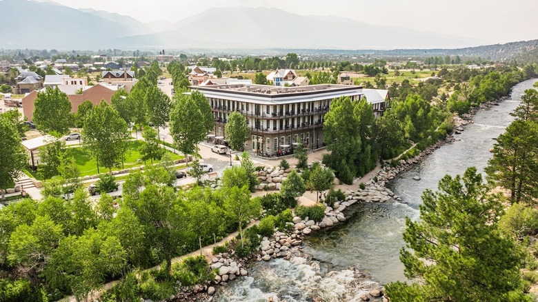 aerial view of hotel along river with mountains in background