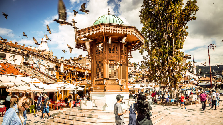 Birds fly around a wooden Sebilj kiosk in Sarajevo old town