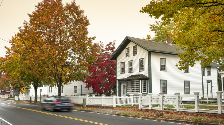 Car on road in small town in Connecticut surrounded by autumn trees