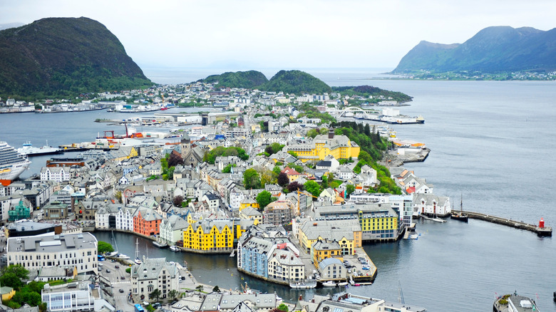 Aerial view of a coastal town with colorful buildings, surrounded by green hills, Ålesund, Norway