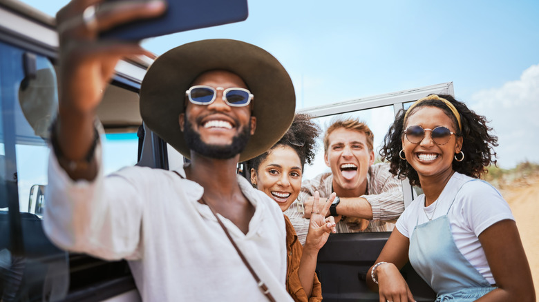 Young group of friends taking a selfie during nature safari vacation in Africa.