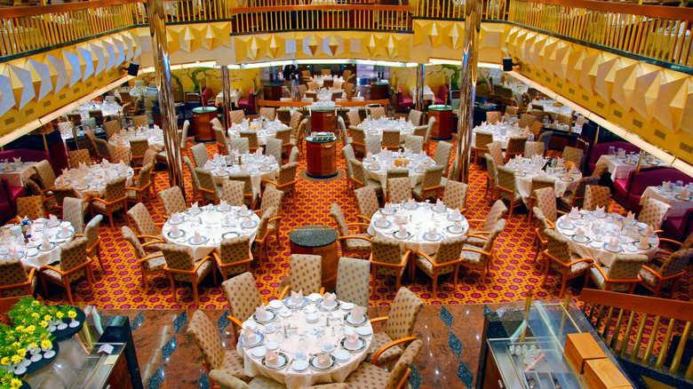 Overview of the dining room, brightly lit and with prepared tables, aboard the Carnival Fantasy cruise ship