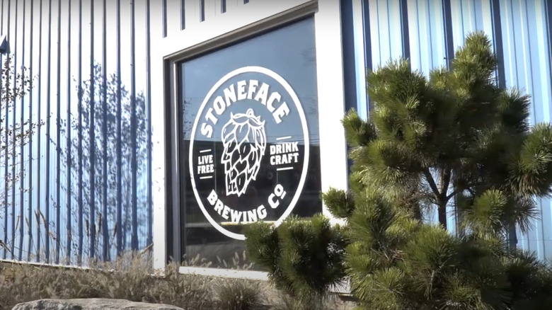 green tree in front of building with sign that reads stoneface brewing in white text