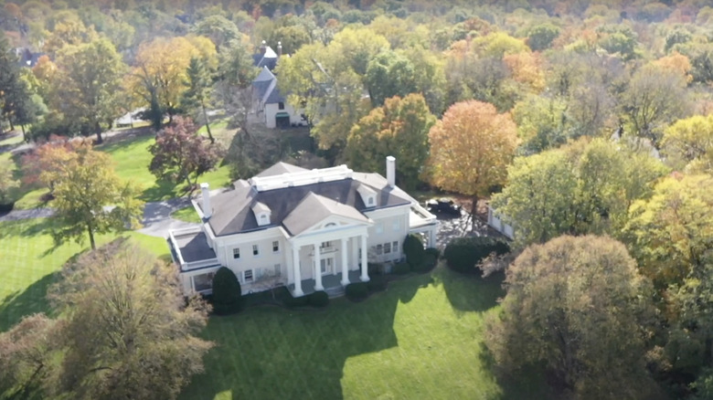 a white mansion on green grass surrounded by colorful trees