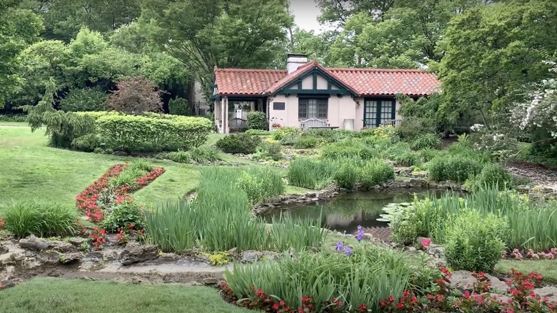 green grass and flowers in front of house under green trees