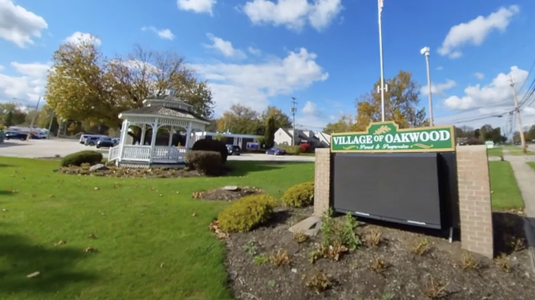 green and white sign on green grass under blue sky