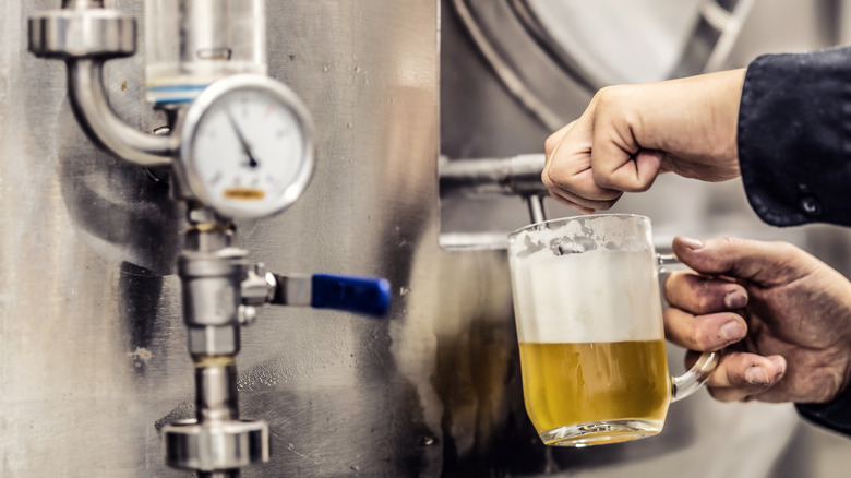 Man filling beer glass at brewery
