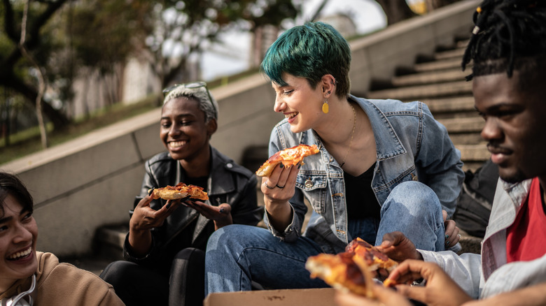 People eating pizza in a park