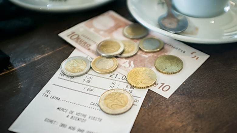 Close-up of a restaurant check sitting on a dining table with Euros as payment