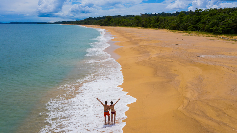 People standing on Bluff Beach on Isla Colon, Panama, with their arms up