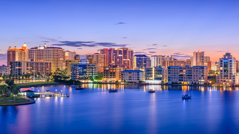 Skyline of Sarasota at sunrise with boats anchored in the bay.