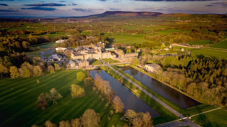 Grand building surrounded by woodland and fields