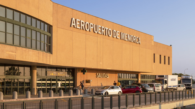 Cars parked outside Menorca Airport during the day.