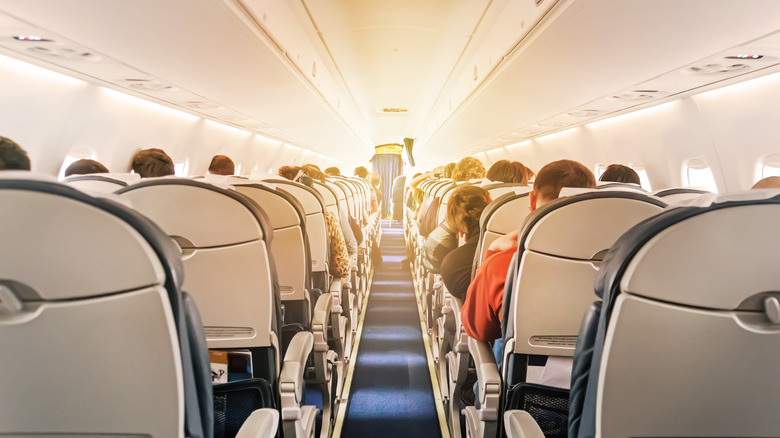 View of a full airplane cabin from the back of the isle