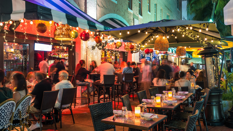 People dining at bustling outdoor cafes along historic Española Way in Miami, Florida