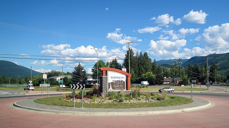 Green mountains loom over roundabout circling sign reading 