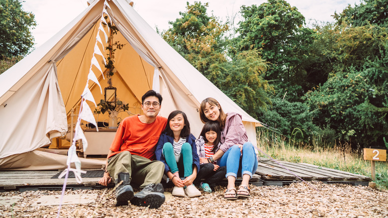 A family of four sitting in front of their tent